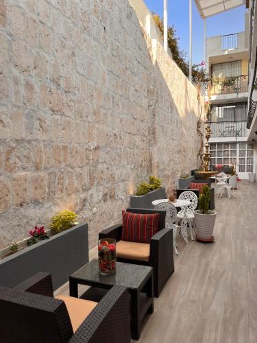 a patio with chairs and tables and a brick wall at Chikan Hoteles in Arequipa