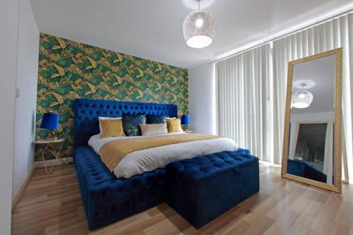 een slaapkamer met een blauw getuft bed en een spiegel bij ChicStay Moura in Birmingham