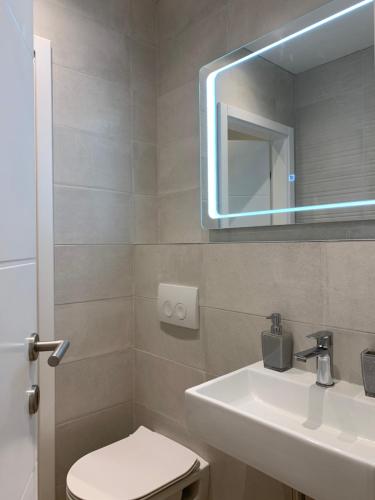 ein Badezimmer mit einem Waschbecken, einem WC und einem Spiegel in der Unterkunft G Apartment in Podstrana