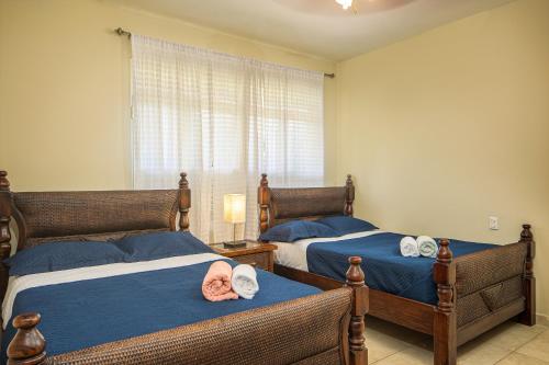 2 camas en un dormitorio con sábanas azules y ventana en Amazing Condos at Sosua Ocean Village, en Sosúa