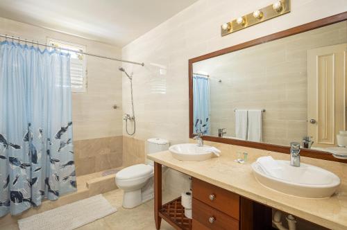 a bathroom with two sinks and a toilet and a mirror at Amazing Condos at Sosua Ocean Village in Sosúa