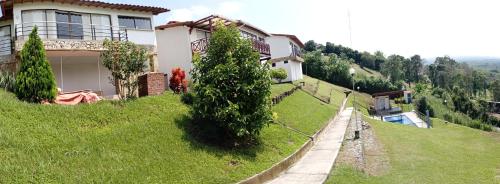 a house on the side of a grassy hill at Apartamento con vista espectacular a 5 minutos del parque del café in Quindío
