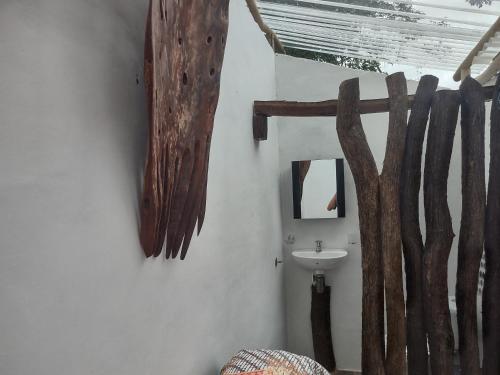 a bathroom with a sink and wooden branches on the wall at The Valley Tayrona hostel- A social jungle hostel in El Zaino