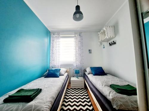 two beds in a small room with blue walls at Zaciszna Przystań in Giżycko