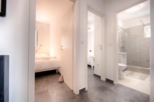 a white bathroom with a bed and a bath tub at Apartmani Dule Komiza in Komiža