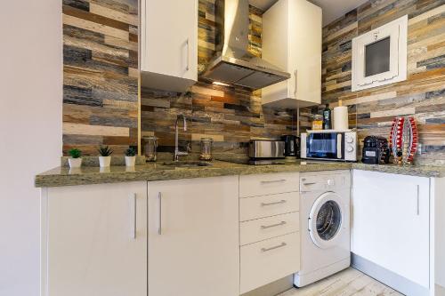a kitchen with white cabinets and a washer and dryer at Sun Coast Benalmádena -- Superb studio with 4 pools, gardens & breakfast in Benalmádena