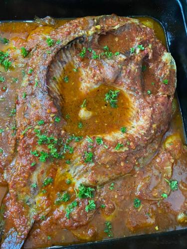 a close up of a steak in a pan with sauce at Pensiunea Califar in Dunavăţu de Jos