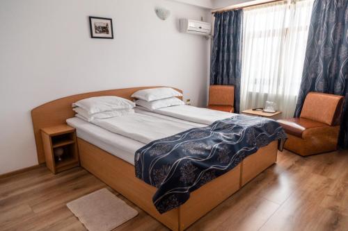 - une chambre avec un lit, une chaise et une fenêtre dans l'établissement Pensiunea Califar, à Dunavăţu de Jos