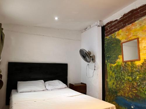 een slaapkamer met een bed en een schilderij aan de muur bij Casa Caballito in León