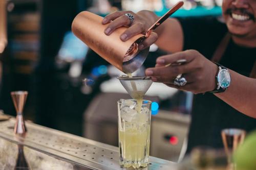 a woman is making a drink at a bar at Crowne Plaza Muscat OCEC by IHG in Muscat