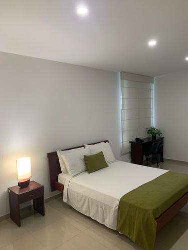 a bedroom with a bed with a lamp and a desk at Hotel Sol de Piedemonte in Yopal
