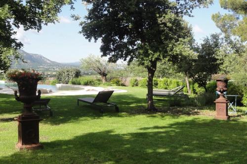 un parco con una panchina e un albero nell'erba di Propriété avec vues panoramiques a Cabrières-dʼAvignon