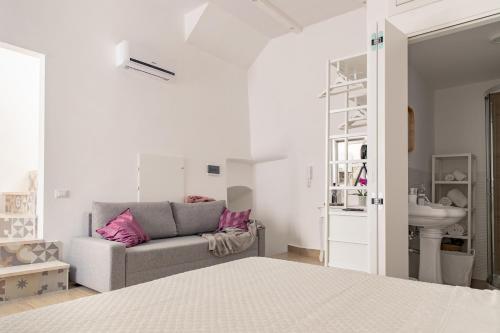 a white bedroom with a couch and a sink at Mare all'Arco Casa Vacanze in Gaeta