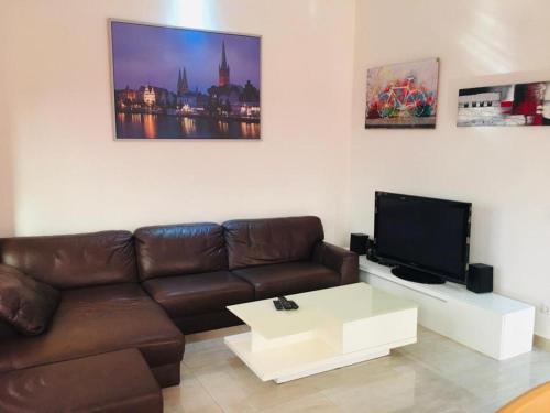 a living room with a brown leather couch and a tv at Villa Cocotiers A11 in Cotonou