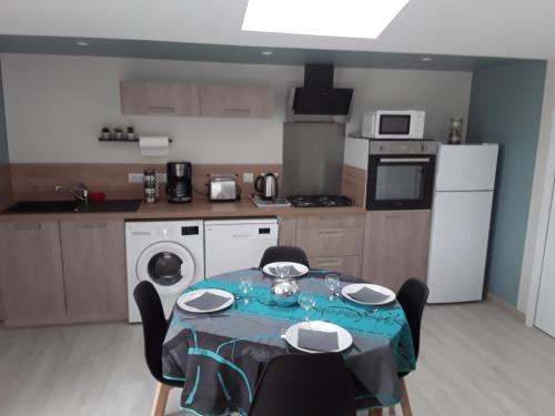 a kitchen with a table and chairs and a kitchen with a table and a table at L'Instant Présent, en Vendée, gite neuf , 3 etoiles, 15 minutes de l'océan in Saint-Julien-des-Landes