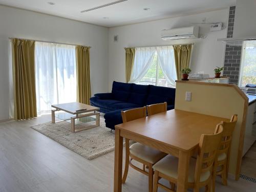 a living room with a table and a blue couch at Holiday Villa 旅生 in Tonosho