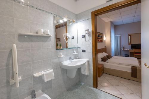 a bathroom with a sink and a toilet and a bed at La Mimosa Lazise in Lazise