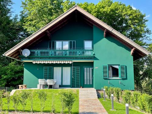 uma casa verde com uma varanda em cima em Chalet beim Georgi Schloss em Ehrenhausen