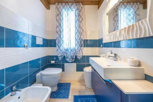 La salle de bains bleue et blanche est pourvue d'un lavabo et de toilettes. dans l'établissement Casa Helen, à SantʼAntìoco