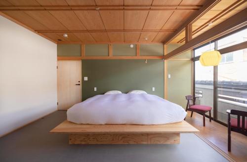 sypialnia z dużym białym łóżkiem na drewnianej ławce w obiekcie Coliving & Cafe SANDO - Vacation STAY 26481v w mieście Imabari