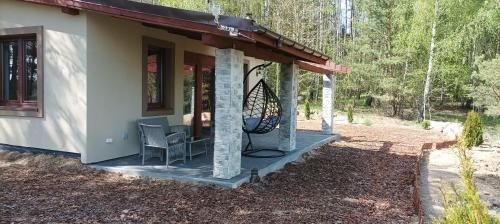 a small house with a porch with a chair on it at Domek Zielenina in Mierzeszyn