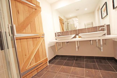 a bathroom with three sinks and a wooden door at Cottage surrounded by woodland and vineyards. in Kent