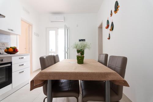 a dining room table with chairs and a vase of flowers at Villa Marisa Holiday Home in Punta Prosciutto