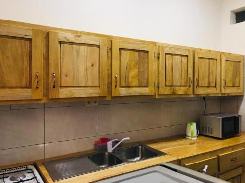 a kitchen with wooden cabinets and a sink and a microwave at Villa Cocotiers A11 in Cotonou