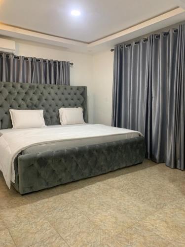 ein Schlafzimmer mit einem großen Bett mit grauen Vorhängen in der Unterkunft Weena Hotel & Resort in Lagos