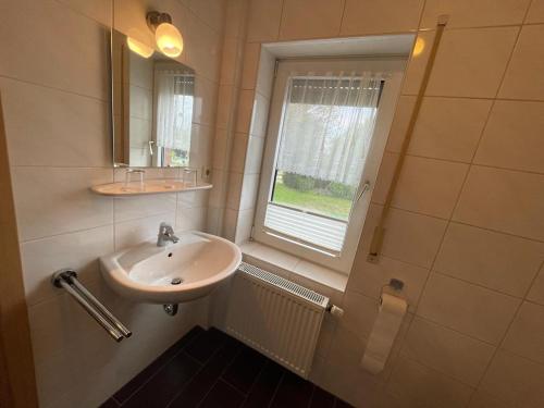 a bathroom with a sink and a window at Pension Restaurant Pizzeria Lion in Krummhörn