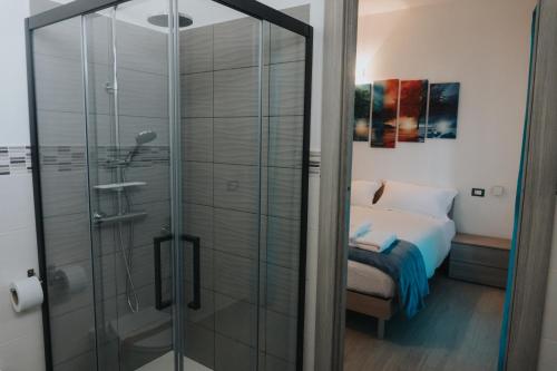 een glazen douche in een slaapkamer met een bed bij Harmony Guest House in Leporano Marina