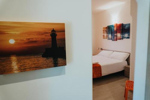 a bedroom with a bed and a painting of a lighthouse at Harmony Guest House in Leporano Marina
