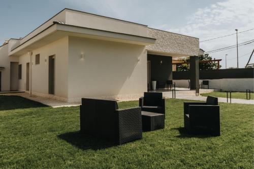 a building with chairs sitting in the grass at Harmony Guest House in Leporano Marina