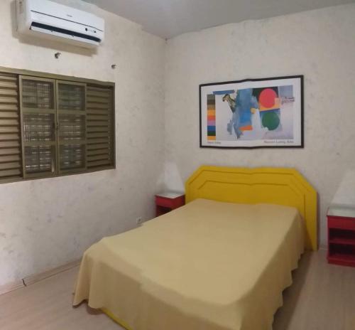 a bedroom with a yellow bed and a window at Flat & Residence Premium - Apês mobiliados e bem equipados in Campo Grande