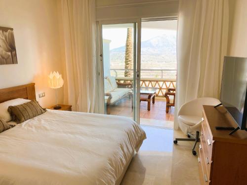 a bedroom with a bed and a television and a balcony at Beautiful luxurious 2 bedroom apartment with a breathtaking view at La Cala Golf in La Cala de Mijas