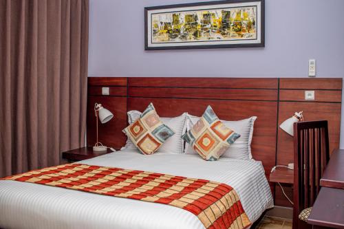 a bedroom with a bed with a blanket and pillows at Résidence Hôtelière Lauria in Lomé
