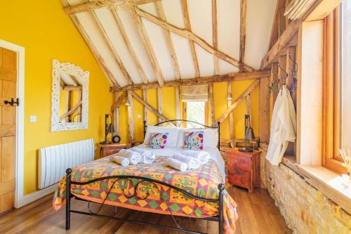 a bedroom with a bed in a room with yellow walls at Watermill Granary Barn in Mendham