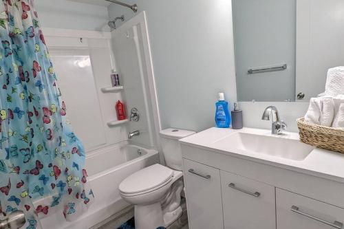 a bathroom with a toilet and a sink and a shower curtain at SERENE & MODERN 1BED SUITE + CLOSE TO AIRPORT in Regina