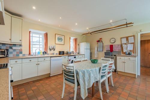a kitchen with a table and chairs in a room at Cwm Farm in Trearddur