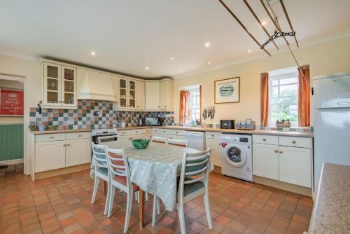 a kitchen with a table and chairs in it at Cwm Farm in Trearddur