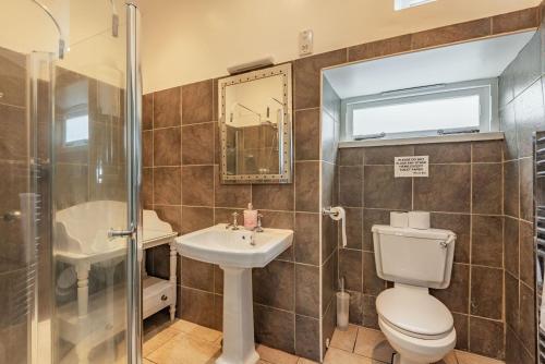 a bathroom with a toilet and a sink and a shower at Cwm Farm in Trearddur