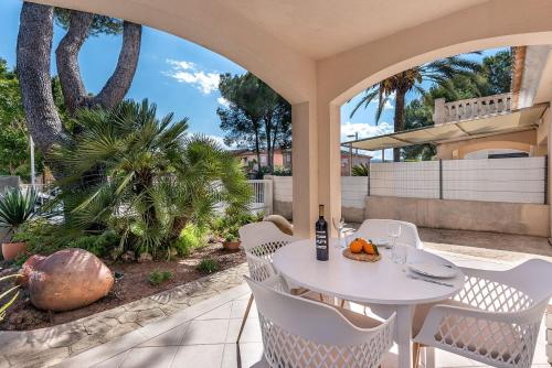 a patio with a white table and chairs and palm trees at Villa Tamarells - Alcúdia in Alcudia