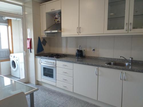 a kitchen with white cabinets and a sink and a microwave at H2OPorto Beachfront Apartment in Vila Nova de Gaia