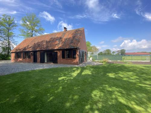 a house with a grassy yard with a roof at Drieskenshoeve in Grote-Brogel
