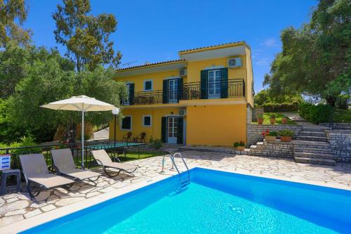 a villa with a swimming pool in front of a house at Villa Joanna in Ágios Stéfanos