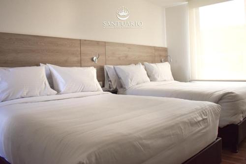 two beds sitting next to each other in a room at HOTEL SANTUARIO in Tunja