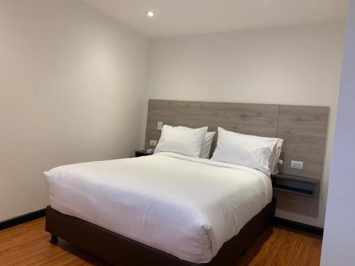 a bedroom with a large bed with white sheets and pillows at HOTEL SANTUARIO in Tunja