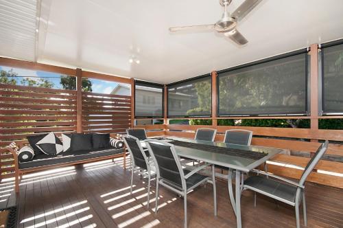 a dining room with a table and chairs and windows at Convent Cottage - Pet-Friendly Central Yamba Escape - Holiday Yamba in Yamba
