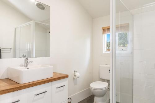 a white bathroom with a sink and a toilet at High Three - Downtown Beach House in Yamba