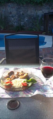 una mesa con un plato de comida y una copa de vino en Habitación en casa con pileta en Río Ceballos en Río Ceballos